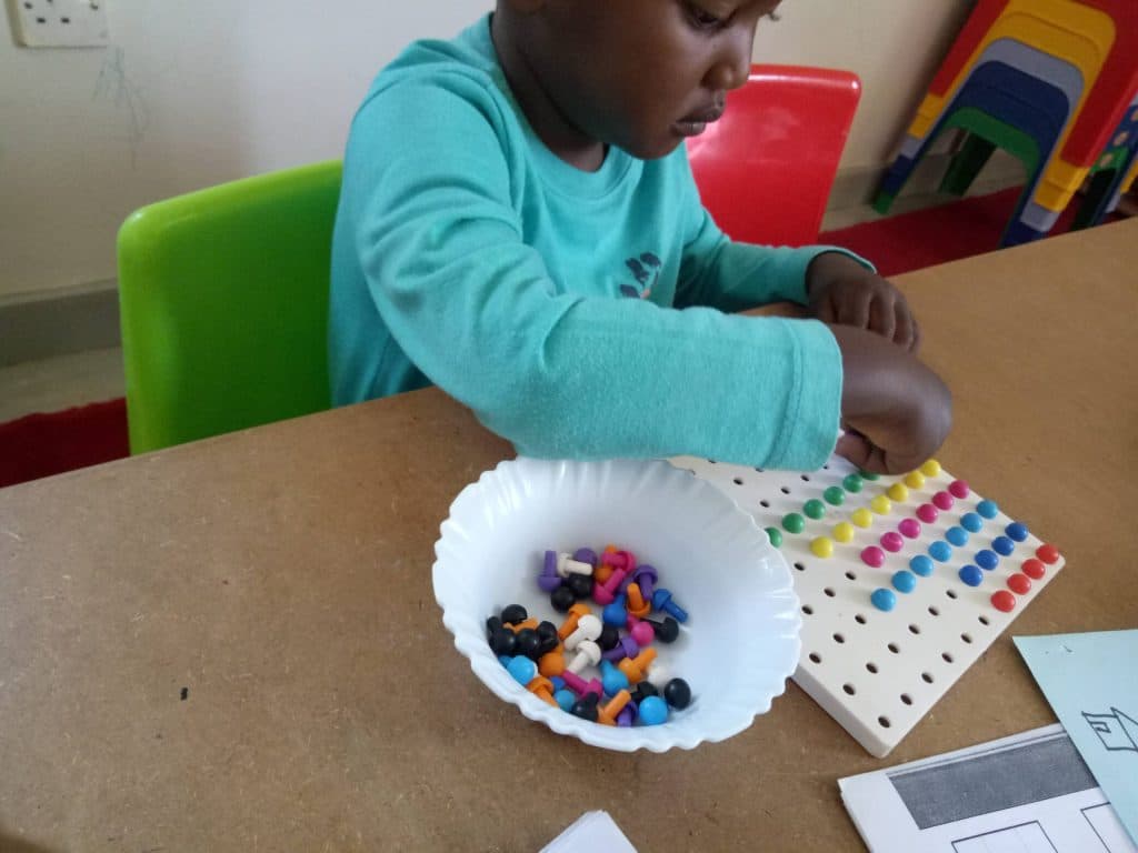 A young child working with a pegboard, building fine-motor control
