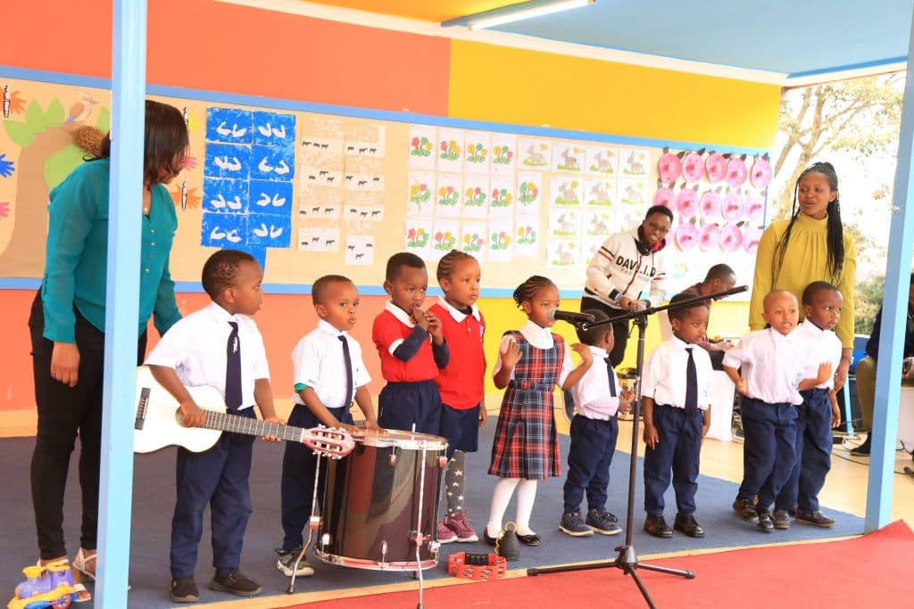 Children performing with guitar and drum at a class concert